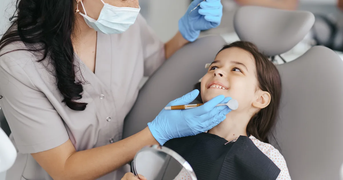 Young girl smiling up at a dentist during a check-up in the dental chair